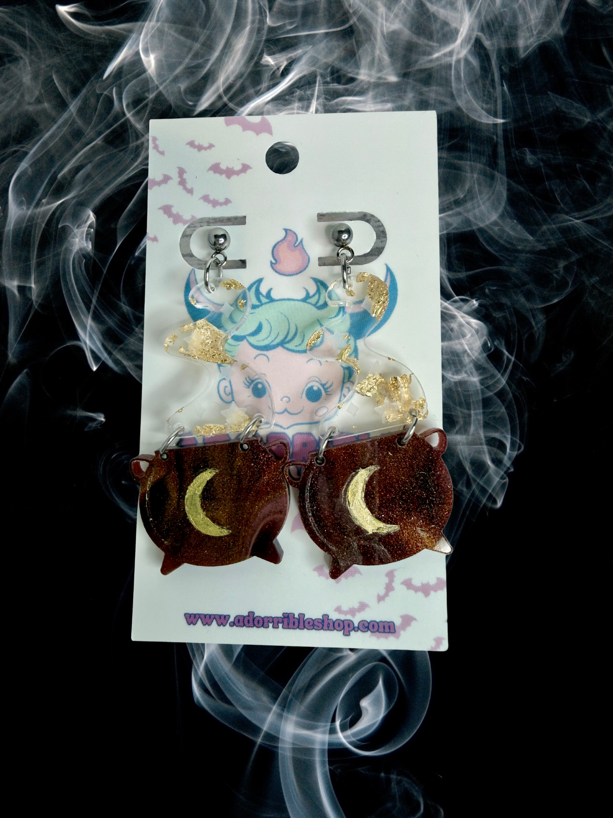 Adorrible witch’s cauldron earrings featuring small black cauldrons with bubbling green potion details.