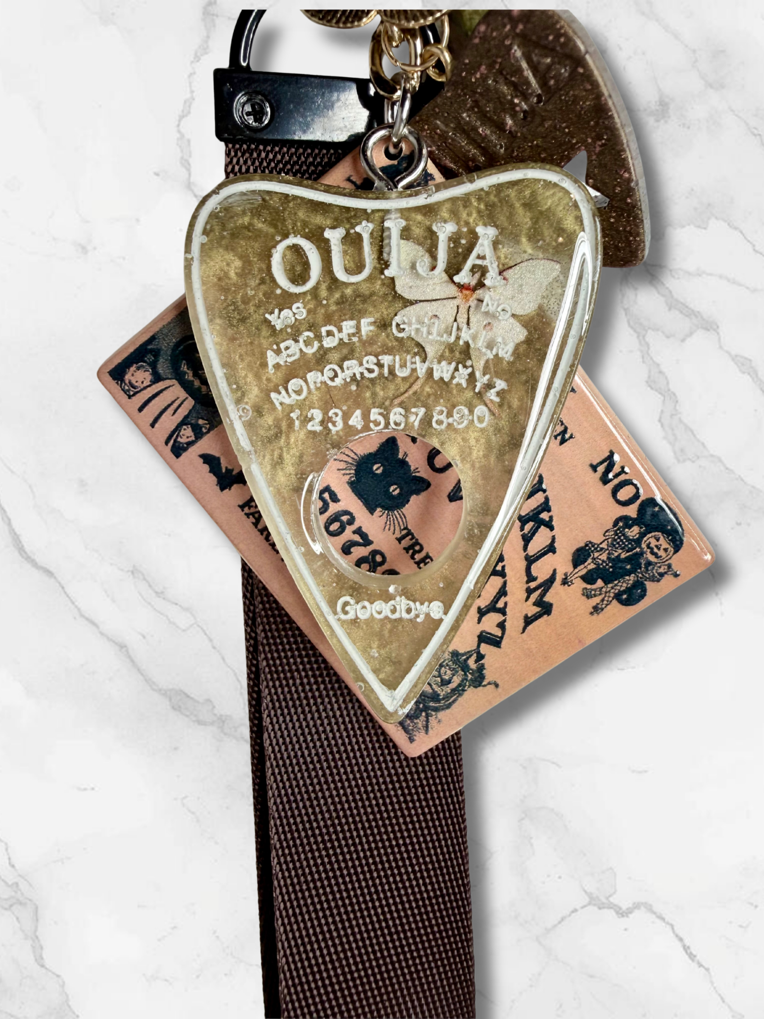 Adorrible Ouija Board keychain with wristlet and spooky charms, featuring mystical symbols and decorative charms for a spooky accessory.