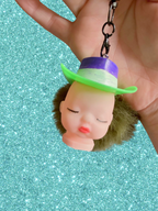 Adorrible Pride cowboy hat baby doll head keychain showing a small doll with a colorful cowboy hat attached to a keyring.