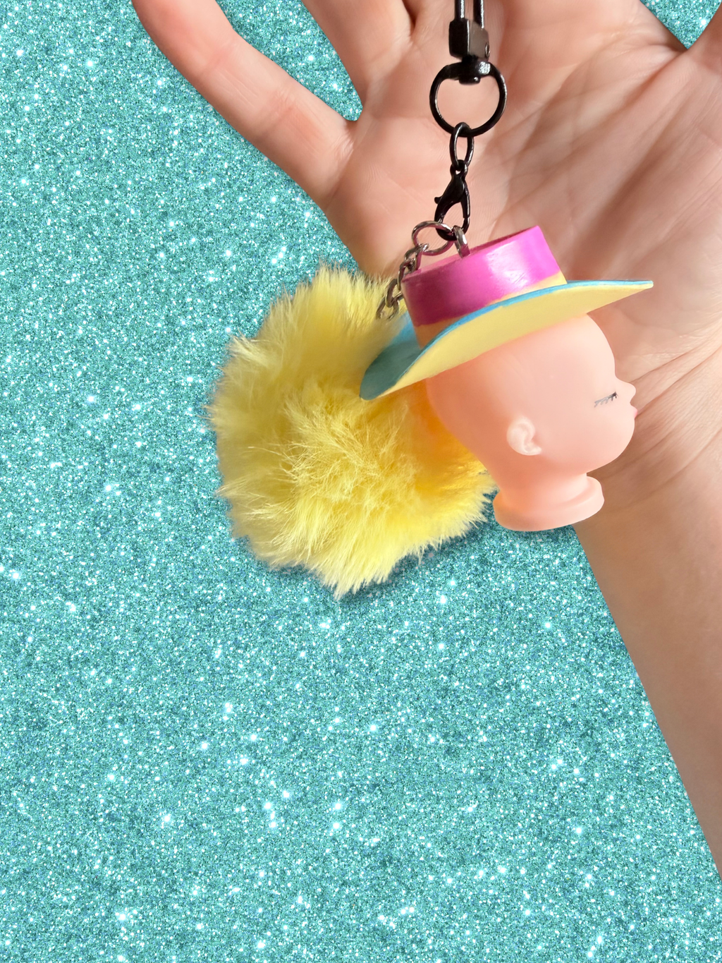 Adorrible Pride cowboy hat baby doll head keychain featuring colorful miniature cowboy hat and doll face, attached to a silver keyring.