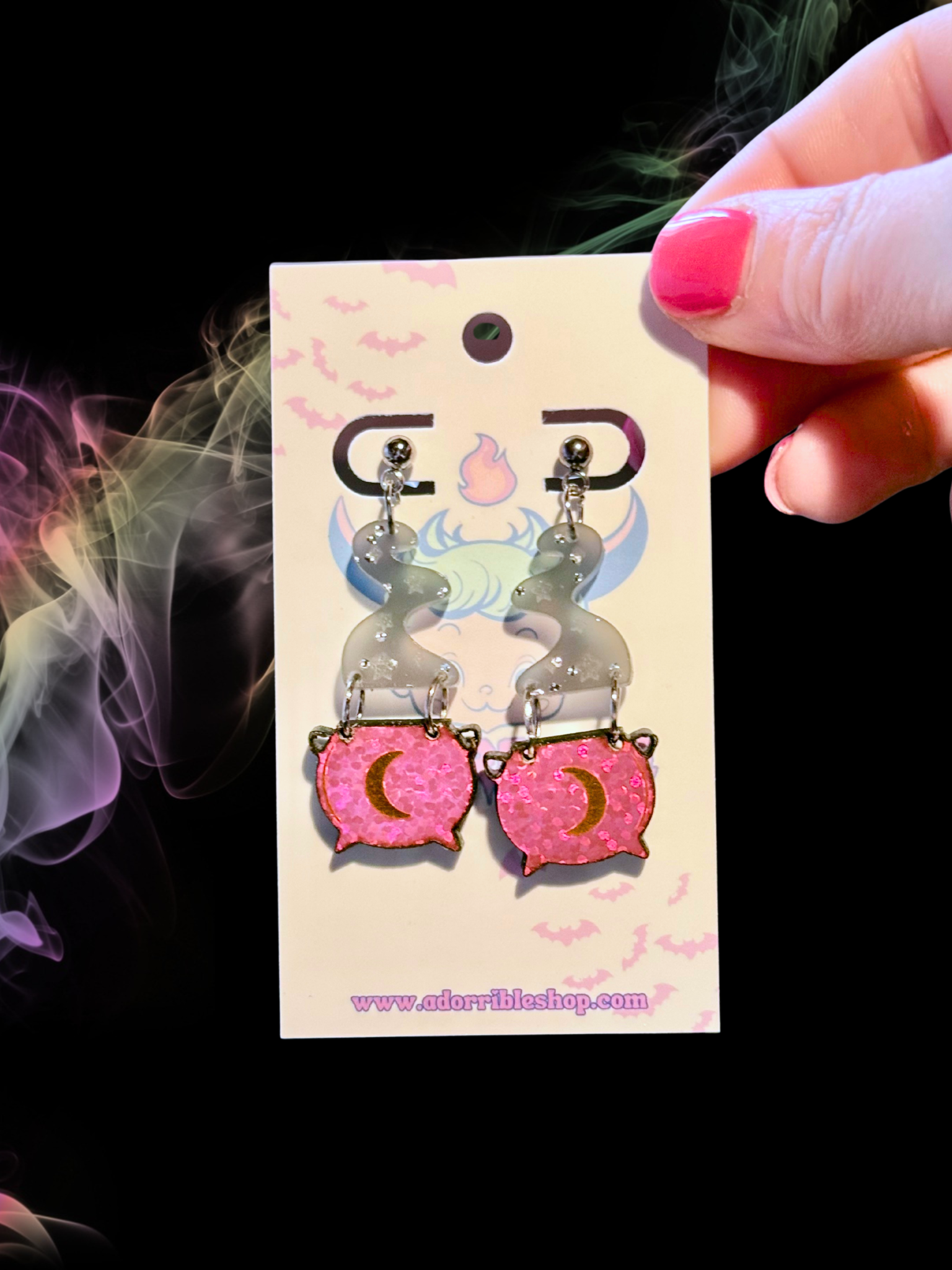 Mini witch’s cauldron earrings by Adorrible featuring tiny black cauldrons with silver accents on hooks.