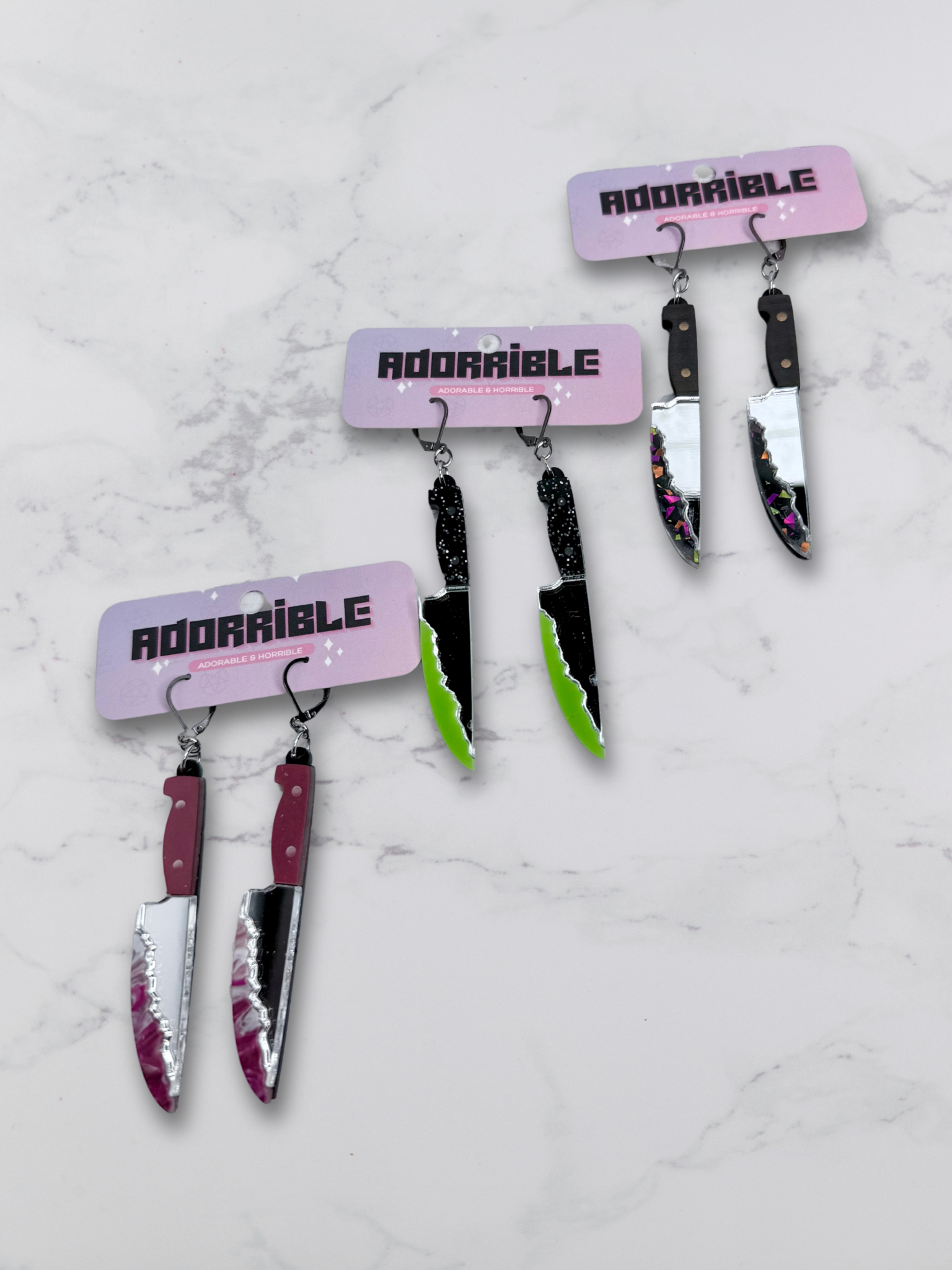 Layered bloody knife dangle earrings by Adorrible featuring dagger-shaped design with layered metal details.