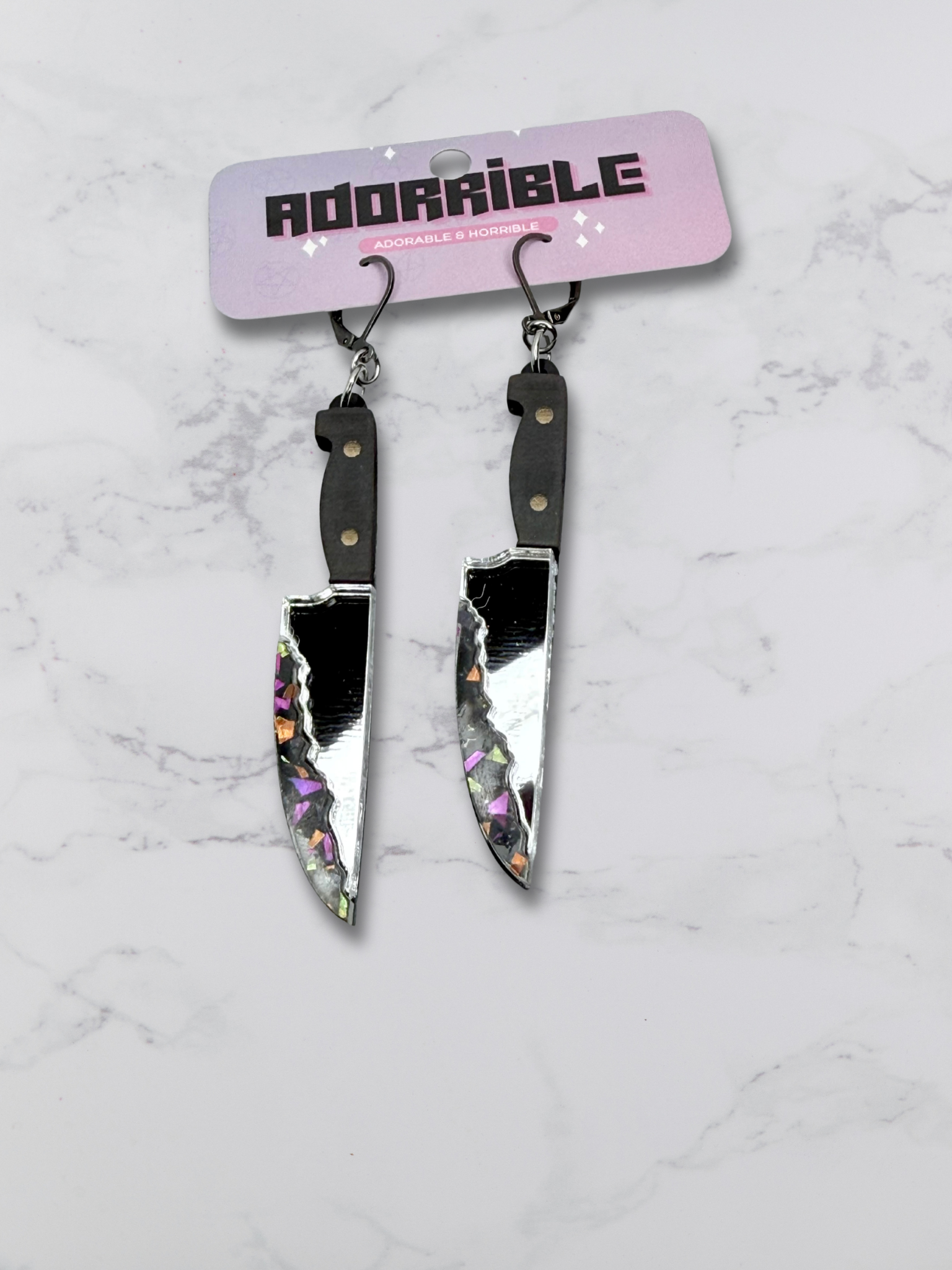 Layered bloody knife dangle earrings by Adorrible featuring dagger-shaped charms hanging from silver hooks.