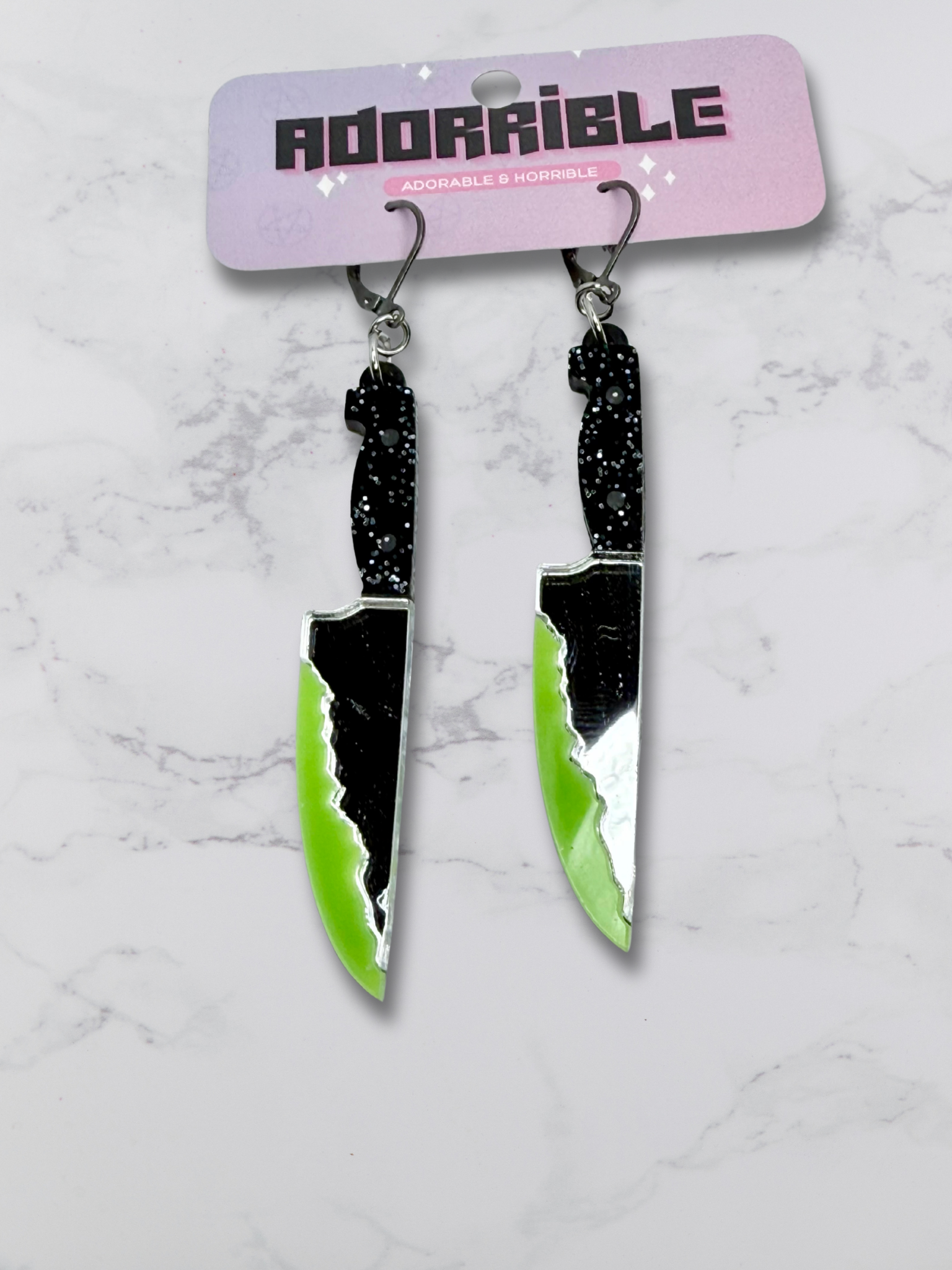 Layered bloody dagger earrings by Adorrible featuring dangling dagger design and layered metal elements on a white background.