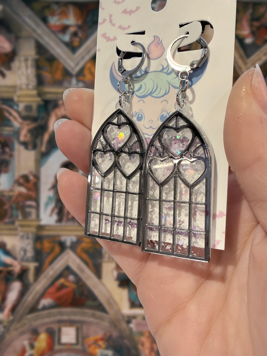 Adorrible Cathedral of Love earrings featuring intricate geometric design and silver finish, hanging from delicate hooks.