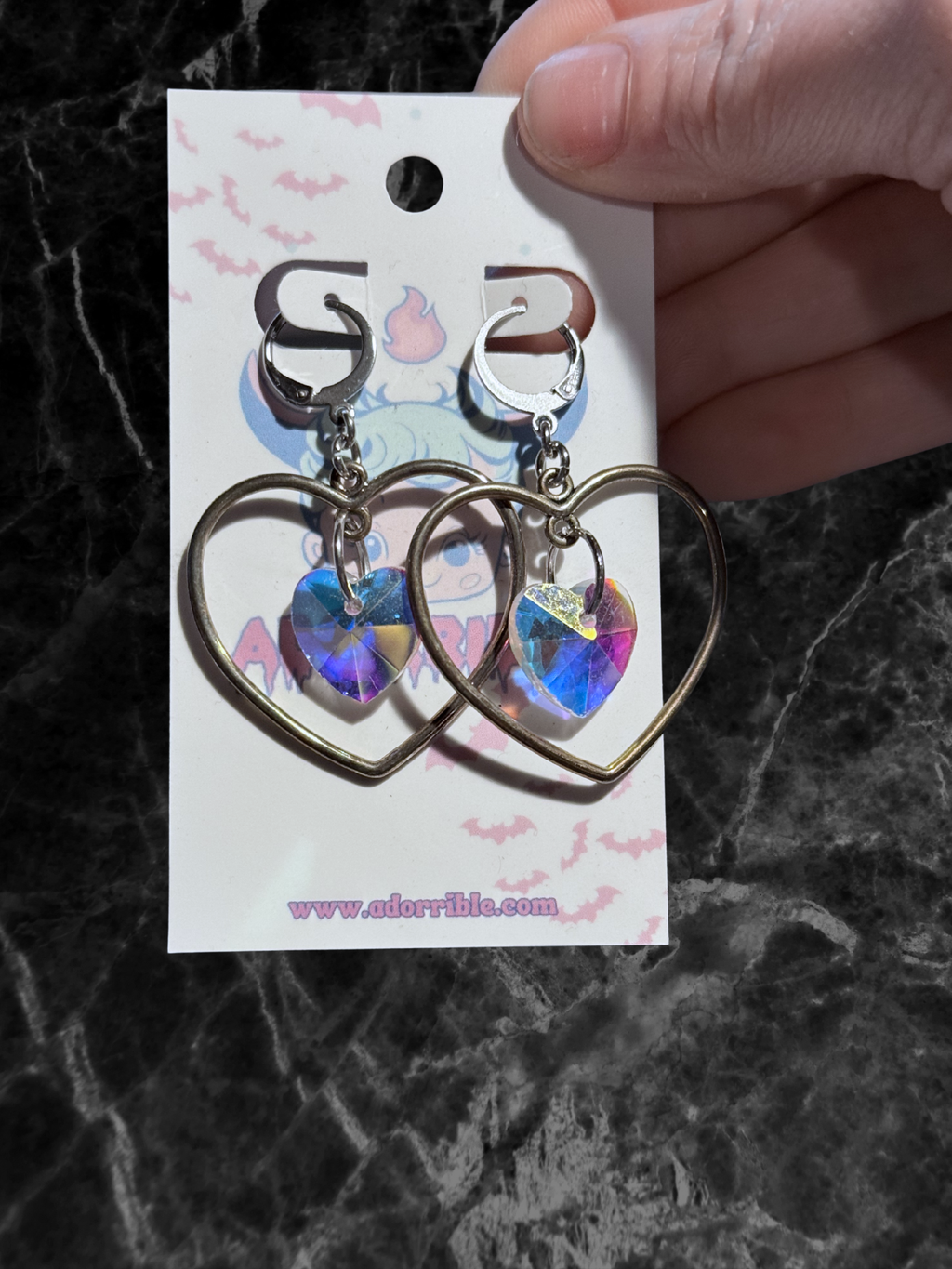 Heart-shaped hoop earrings with sparkling heart crystals by Adorrible, featuring shiny metal hoops and detailed crystal accents.