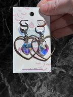 Heart-shaped hoop earrings with sparkling heart crystals by Adorrible, featuring shiny metal hoops and detailed crystal accents.