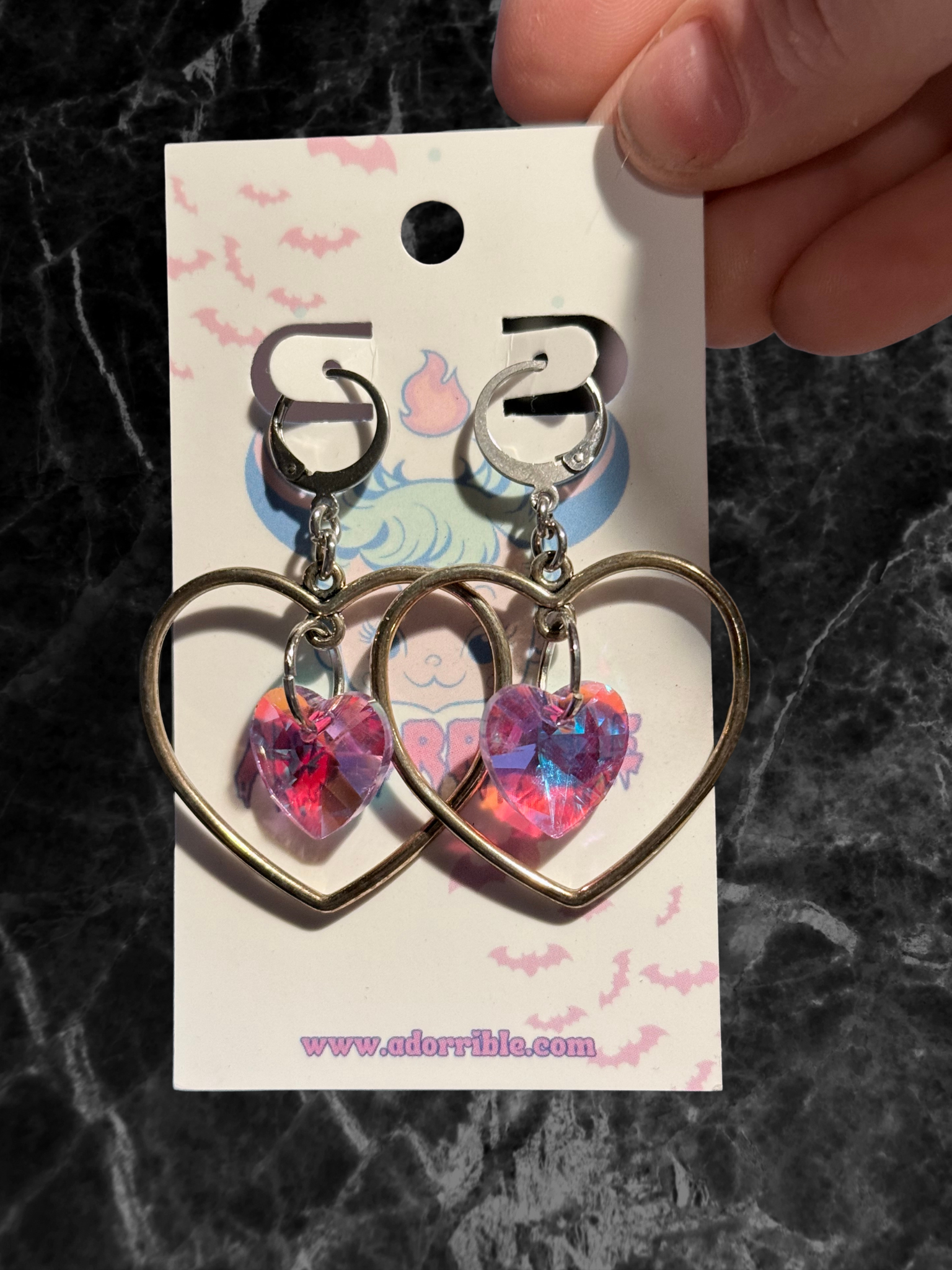 Heart-shaped hoop earrings with sparkling heart crystals by Adorrible, featuring shiny metal hoops and delicate crystal accents.
