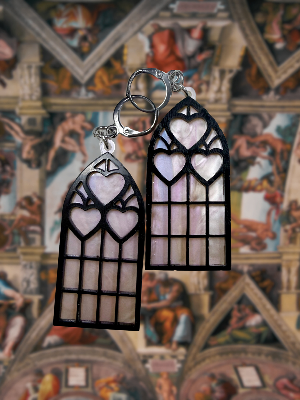 Adorrible Cathedral of Love acrylic dangle earrings featuring intricate design and vibrant colors, hanging from silver hooks.