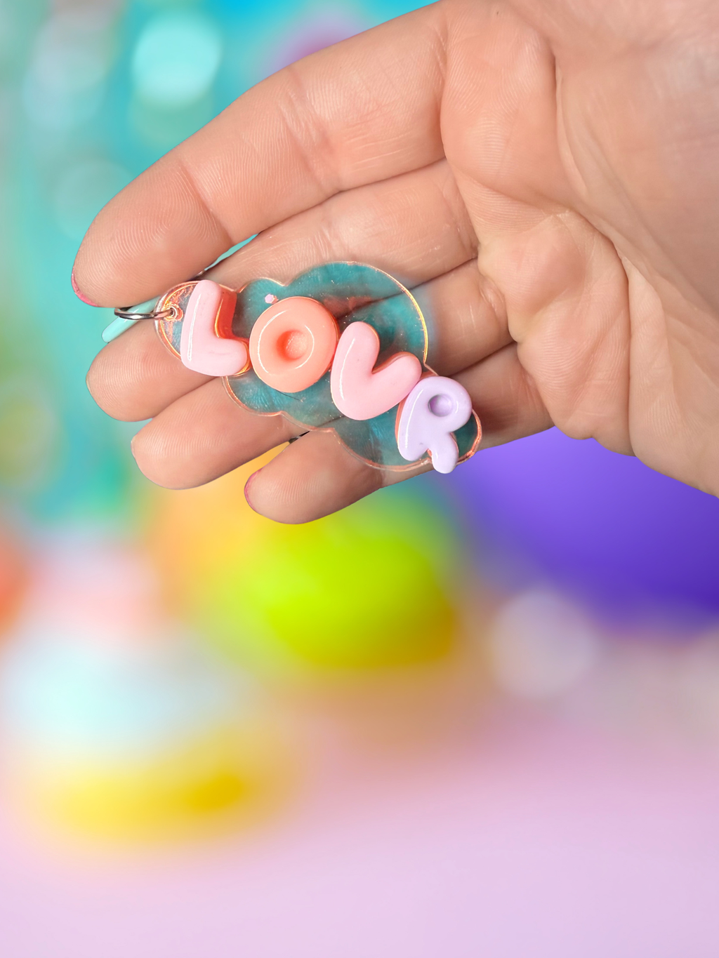 Iridescent cloud keychain with bubble letter design by Adorrible hanging from a silver keyring.