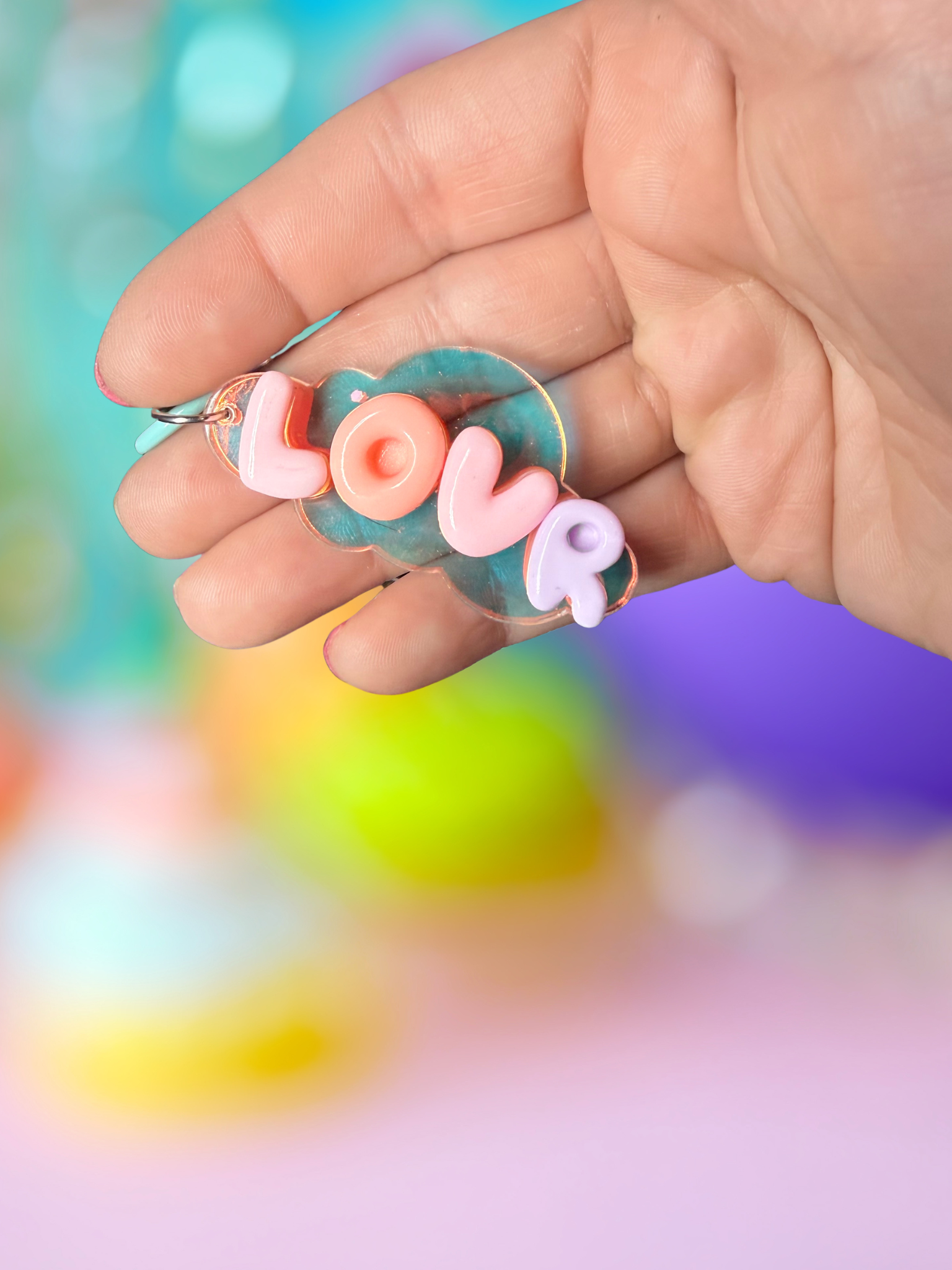 Iridescent cloud keychain with bubble letter design by Adorrible hanging from a silver keyring.
