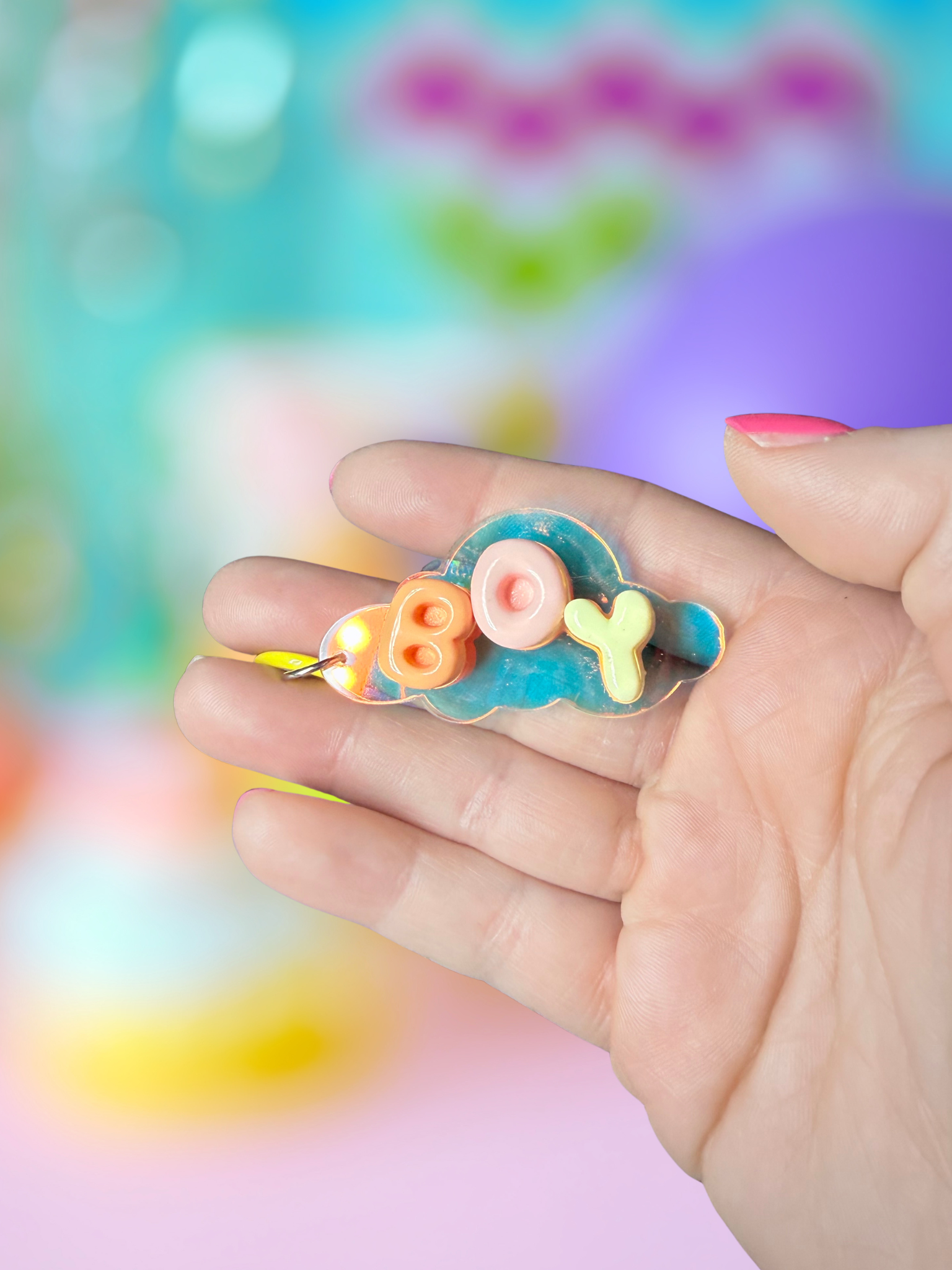 Iridescent cloud-shaped keychain with bubble letter design by Adorrible, featuring shiny, colorful material and a metal keyring attachment.