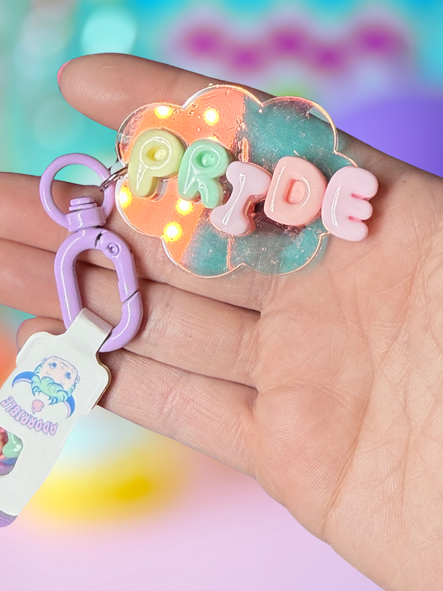 Iridescent cloud keychain with bubble letter design by Adorrible hanging from a silver keyring.